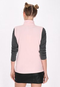 Gilet senza maniche rosa con maniche lunghe grigie, caratterizzato da un colletto alto e una texture liscia, progettato con un taglio dritto e cuciture laterali.