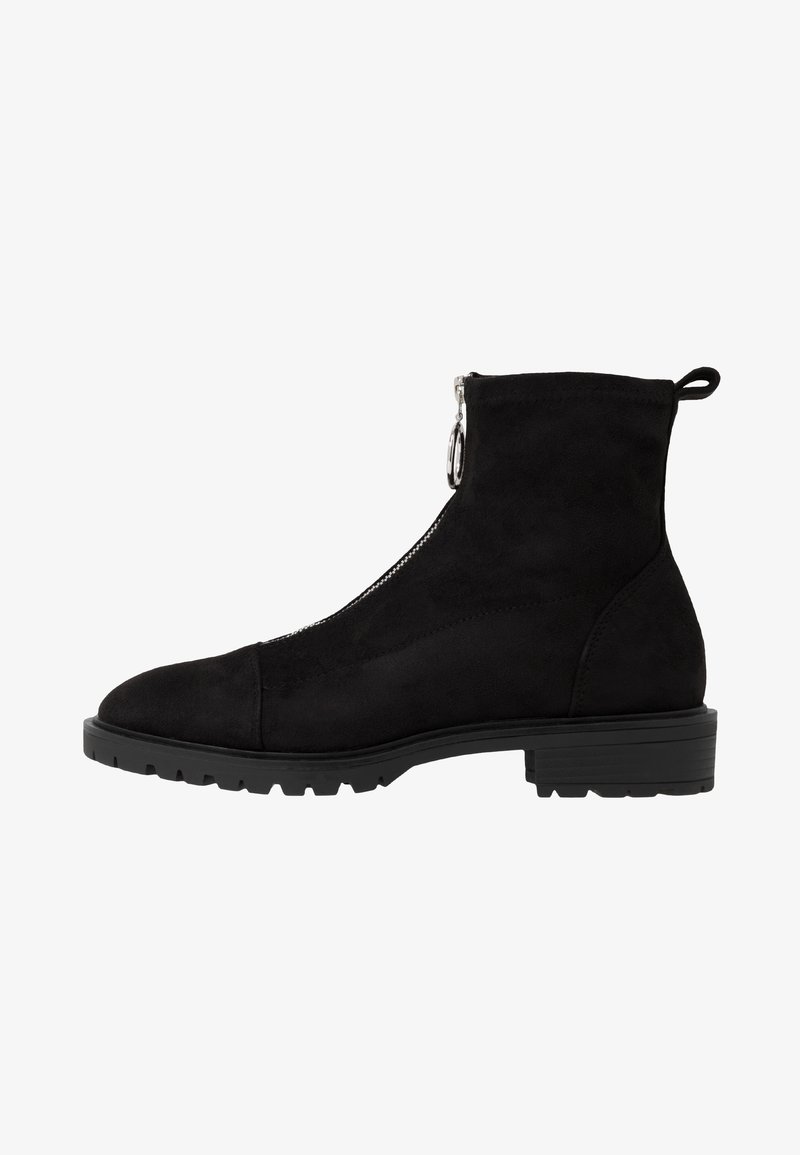 Bottes cheville en suède noir avec une fermeture éclair sur le côté, bout rond et semelle texturée. Dotées d'une languette à l'arrière et d'un talon épais.