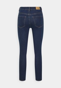 Tmavě modré skinny džíny s hladkou texturou, s páskem v poloviční výšce, pěticípým designem a jemnými detaily šití.