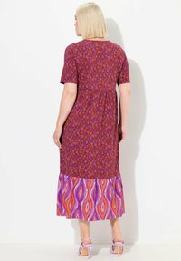 Maxikleid mit floralem Muster und kurzen Ärmeln in Mahagoni- und Lilatönen. Verfügt über einen gestuften Rock mit einem welligen, bunten unteren Panel.