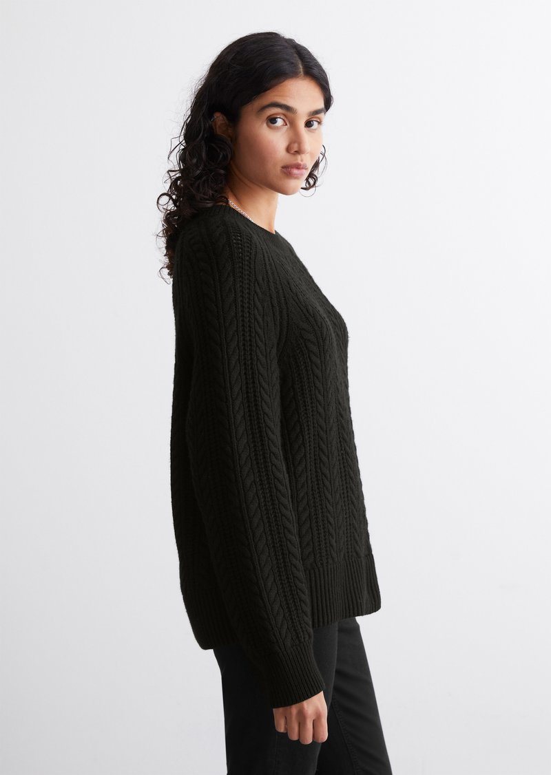 Schwarzer gestrickter Pullover mit einem Zopfmuster, langen Ärmeln und Rundhalsausschnitt. Der Stoff hat ein strukturiertes, dickes Aussehen.