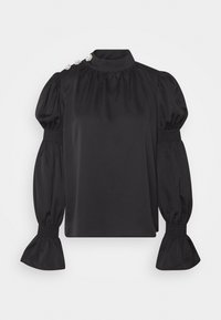 Blouse noire à col montant, manches bouffantes et poignets smockés. Présente des boutons décoratifs sur une épaule. Texture du tissu lisse.