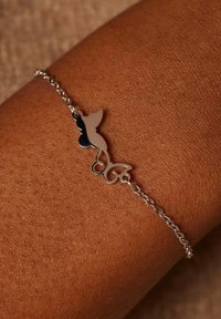 Zilveren armband met een vlinderontwerp en een gesplitst kleurenpatroon. De ketting is delicaat met een fijne linktextuur.