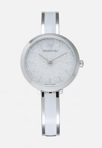 Orologio in metallo argentato con quadrante rotondo. Cassa bianca scintillante con texture, lancette argentate e un elegante bracciale. Fabbricato in Svizzera.