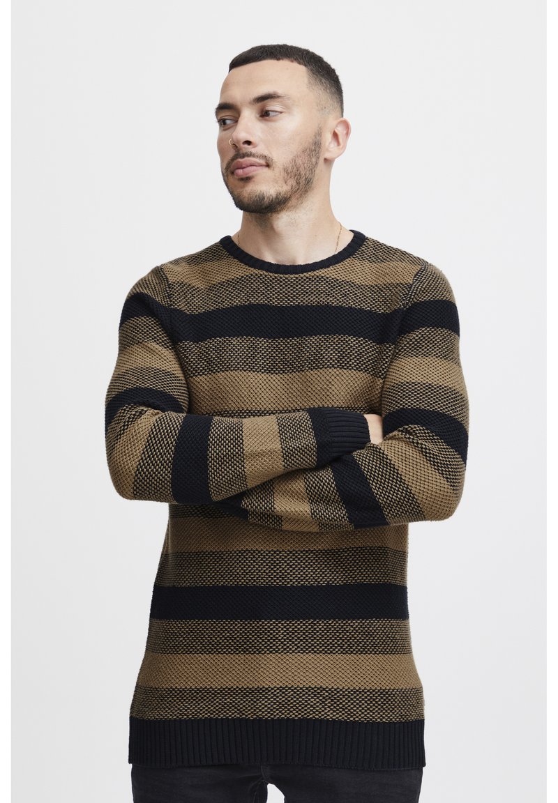Il maglione a righe presenta strisce orizzontali marroni e nere, un tessuto a maglia testurizzato, collo rotondo e polsini e orlo a costine.