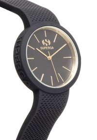 Reloj de silicona negro con un diseño minimalista, cara redonda, acentos dorados y una correa texturizada. Logo de la marca "SUPERGA" prominentemente visible.