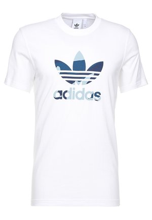 T-shirt Adidas blanc à manches courtes avec logo trèfle camouflage bleu et texte Adidas centrés sur le devant.