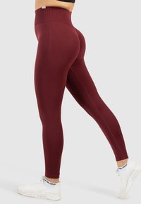 Bordeaux leggings in een strakke pasvorm met textuuraccenten langs de zijkanten, voorzien van een hoge tailleband en naadloze constructie. Draag ze met witte sneakers.