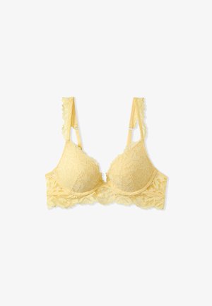 Soutien-gorge en dentelle de couleur jaune clair avec un motif floral. Il présente des bords festonnés, des bretelles réglables et une finition lisse sur les bonnets.