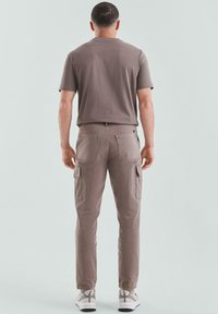 Bruine katoenen t-shirt met korte mouwen, gecombineerd met beige cargo shorts met twee zijzakken, een slim fit en elastische enkels.