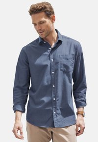 Button-up-Hemd aus dunkelblauem Stoff mit glatter Textur, langen Ärmeln und einer Tasche auf der linken Seite. Verfügt über weiße Knöpfe.