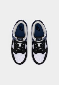 Ζεύγος μαύρων, λευκών και μπλε αθλητικών παπουτσιών Nike με δεμένα κορδόνια, βλέποντας από πάνω σε λευκό φόντο.