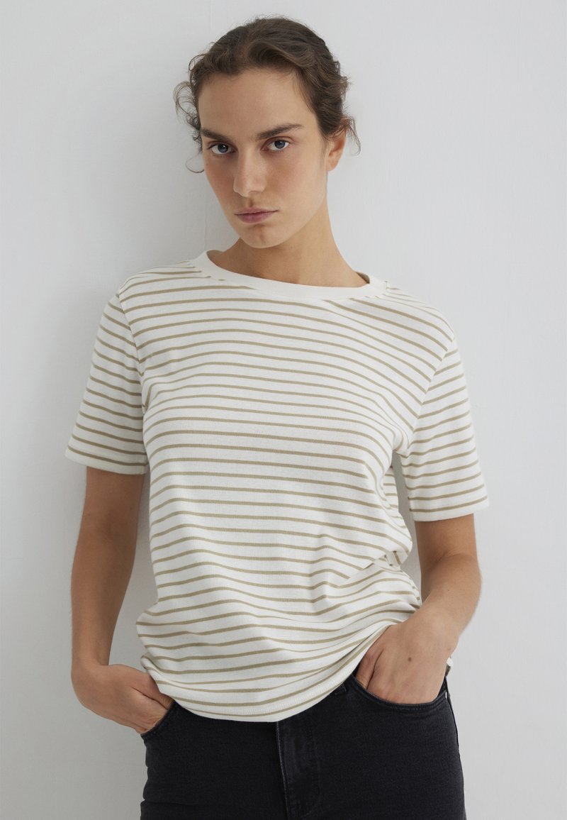 Kurzärmeliges T-Shirt aus weicher Baumwolle, mit horizontalen beigen Streifen auf weißem Hintergrund, locker sitzend und mit rundem Ausschnitt.
