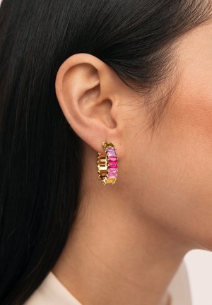 Pendiente de aro dorado con gemas rectangulares alternadas en rosa y púrpura, llevado en la oreja izquierda contra cabello oscuro y piel clara.
