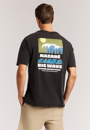 Zwart katoenen T-shirt met een kleurrijke afbeelding van golven, zon en tekst op de achterkant. Korte mouwen en een losse pasvorm.