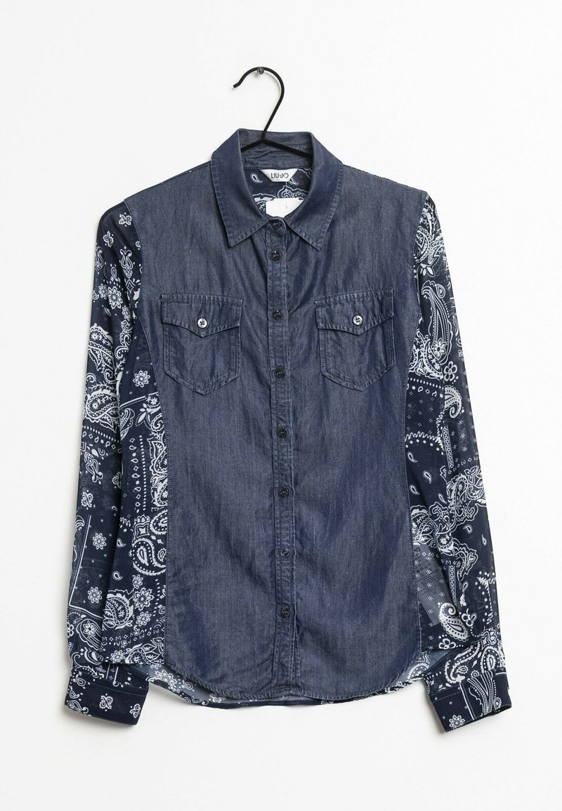Camisa de mezclilla con un frente azul oscuro y mangas de estilo bandana con estampado. Incluye dos bolsillos frontales y cierre de botones.