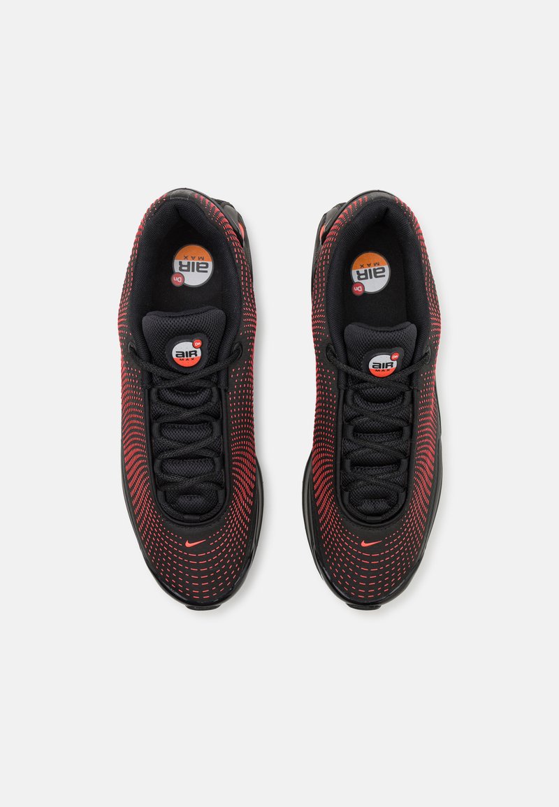 Baskets de sport noires et rouges avec tige en maille, motif texturé et lacets noirs. Présente un amorti visible et un logo rond sur la semelle intérieure.