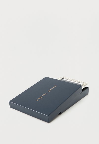 Σκούρο μπλε κουτί Ralph Lauren εν μέρει ανοιχτό, αποκαλύπτοντας μια ασημένια ορθογώνια αγκράφα ζώνης με αλυσίδα στο εσωτερικό.