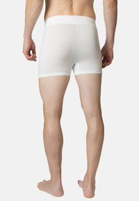 Boxer-briefs ajustés blancs, texture lisse, taille élastique, longueur mi-cuisses, avec un design en mesh respirant à l'arrière et sur les côtés.