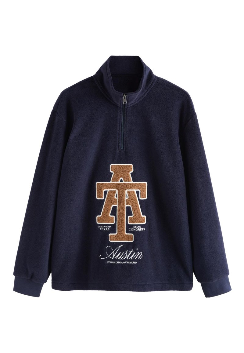 Marineblauer Fleece-Pullover mit Reißverschluss am Kragen. Verfügt über ein großes braunes "AT"-Logo und eine "Austin"-Stickerei in der Mitte, akzentuiert mit weißem Text.