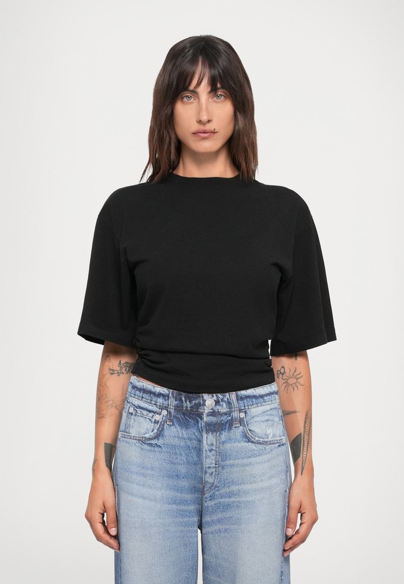Svart t-skjorte med kort erm og rund hals, har en tettsittende silhuett. Kombinert med lyseblå high-waisted jeans som viser en falmet tekstur.