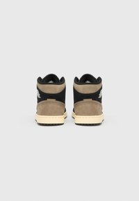 Ténis de cano alto com mistura de camurça preta e castanha, sola intermédia creme e logótipo no calcanhar. Detalhe em tecido texturado.