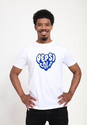 Bílá bavlněná tričko s velkým modrým grafickým nápisem "PEPSI COLA" v tučném, hravém písmu. Krátké rukávy, kulatý výstřih, volný střih.