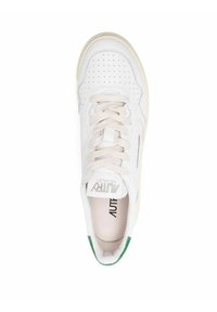 Scarpa sportiva bianca con tomaia in pelle perforata, lacci beige e accentuazione verde sul tallone. Presenta un logo sulla linguetta e un morbido rivestimento interno.