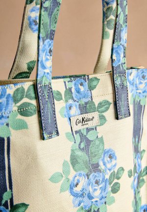 Plátěná taška s květinovým vzorem modrých růží a zelených listů; má modré a navy popruhy; obsahuje štítek Cath Kidston.