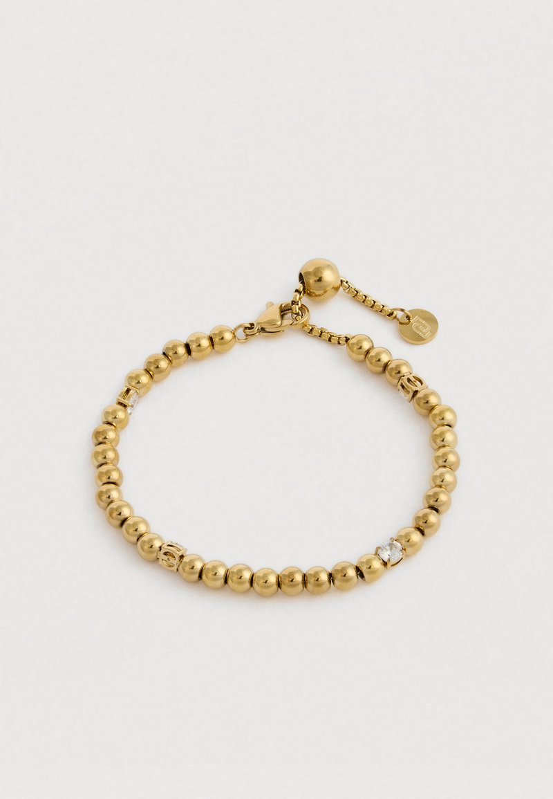 Kuldne helmestest käevõru, millel on vähklöögi klamber, väike kett pikendamiseks ja selge pöörise aksent valgel taustal.