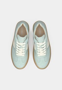 Paire de baskets en daim bleu clair avec des rayures blanches, des lacets crème et des semelles en caoutchouc gomme, vues de dessus sur un fond blanc.