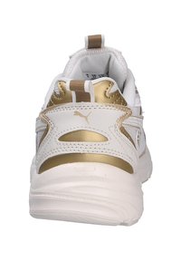 Sneaker bianca con dettagli dorati, dotata di un tallone testurizzato, colletto imbottito e una miscela di materiali sintetici in un design elegante.