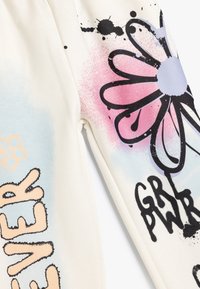Sweatshirt aus weichem Elfenbein stoff mit einem großen schwarzen Blumenmotiv, bunten Farbspritzern und verspieltem Text in verschiedenen Farben.