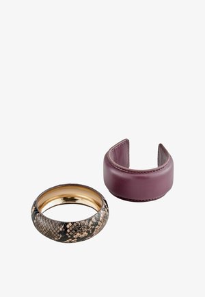 Zwei Manschettenarmbänder: eines mit Schlangenlederstruktur und goldenem Innenfutter, das andere aus glattem, dunkelviolettem Leder mit offenem Ende.