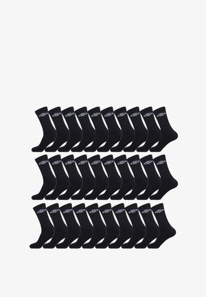 Chaussettes en coton noir disposées en grille, avec un logo blanc sur le revers. Texture douce et design mi-mollet.