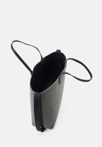 Sac fourre-tout gris avec des poignées noires et un dessus ouvert montrant une doublure intérieure sombre et spacieuse.
