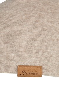 Beige textured fabric with a small brown leather tag stitched at the bottom, embossed with the brand name "Sterntaler."