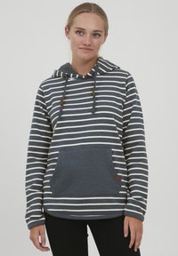 Sudadera con capucha en azul marino con rayas horizontales blancas. Cuenta con un bolsillo frontal y cordones con detalles de madera. Textura suave.