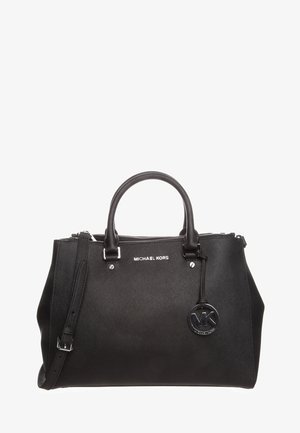 Sac à main Michael Kors noir avec double poignée, bandoulière amovible, et pendentif rond avec logo MK suspendu à l'avant.
