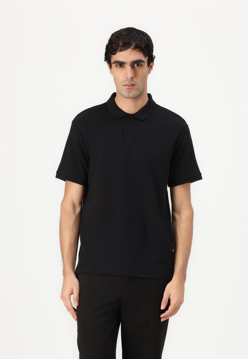 Zwarte polo shirt gemaakt van katoen, met een kraag, een drieknoopsluiting en korte mouwen; gladde textuur zonder zichtbare patronen.
