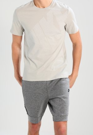 Jasnoszara koszulka z delikatnym wzorem i okrągłym dekoltem, zestawiona z szarymi szortami z bocznymi kieszeniami i czarnym akcentem logo.