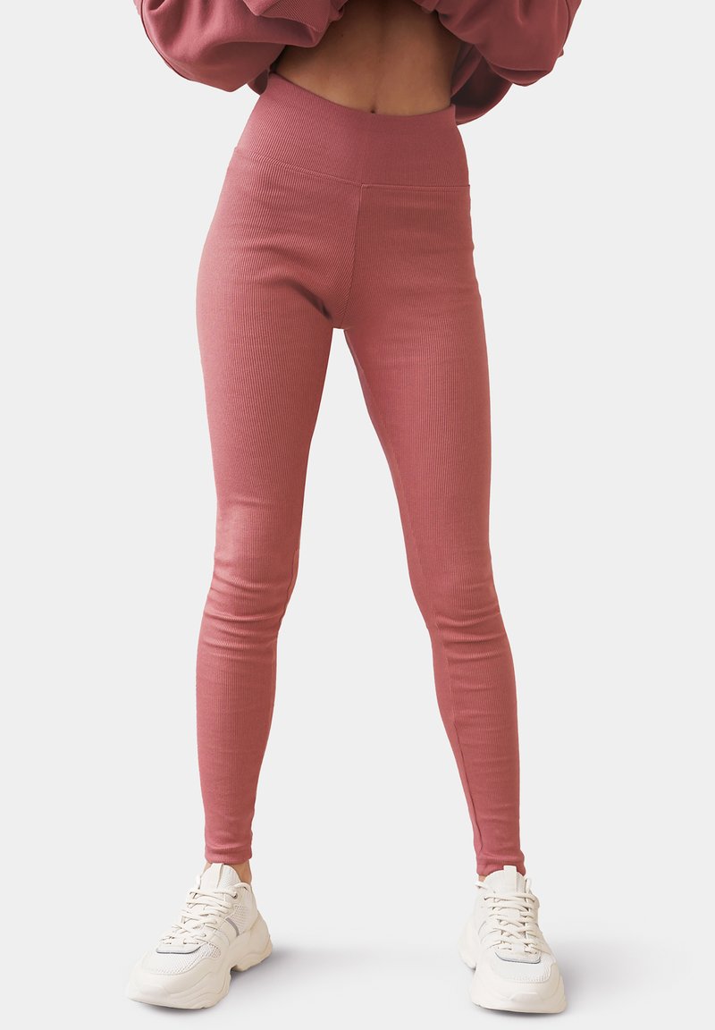 Rostfärgade ribbade leggings med hög midja, med en åtsittande design och slät yta, kombinerade med vita träningsskor.