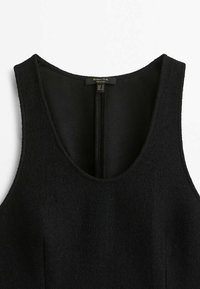 Robe noire en laine sans manches avec encolure dégagée et fermeture éclair au dos, petite étiquette de marque à l'intérieur du col.