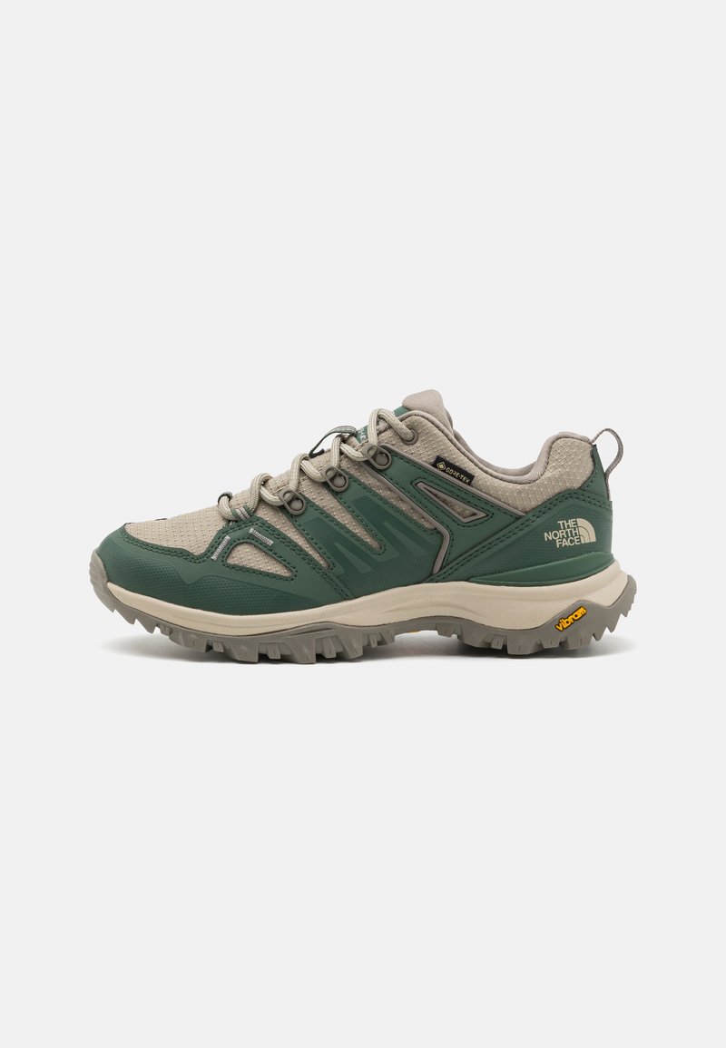 Trail-sko i grøn og beige, der har mesh- og syntetiske materialer, en robust sål og et fremtrædende logo på hælen.