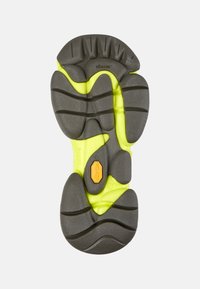 Černá a žlutá podrážka z Vibram gumy s hlubokými drážkami a strukturovanými vzory pro zvýšenou přilnavost a flexibilitu.