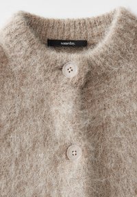 Beige fuzzy knit cardigan with ribbed collar, two beige buttons, and a black label reading "someday." at the neckline.