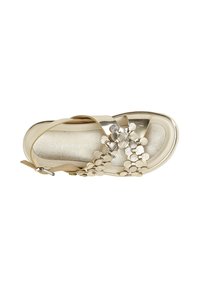 Beige sandal with a shiny, metallic finish. Features decorative cluster of circular accents at the front. Adjustable ankle strap included.