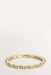 Anillo de oro con tachuelas en forma de pirámide alternas y pequeños diamantes redondos engastados a lo largo de la banda, exhibido sobre un fondo neutro.