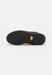 Semelle extérieure en caoutchouc noir avec des motifs de semelle profonds ; logo Vibram jaune ; talon renforcé ; texture durable pour une traction sur diverses surfaces.