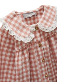 Robe à carreaux en tissu rose et blanc, dotée d'un col en dentelle et de boutons en bois. Comprend des détails froncés à la taille.